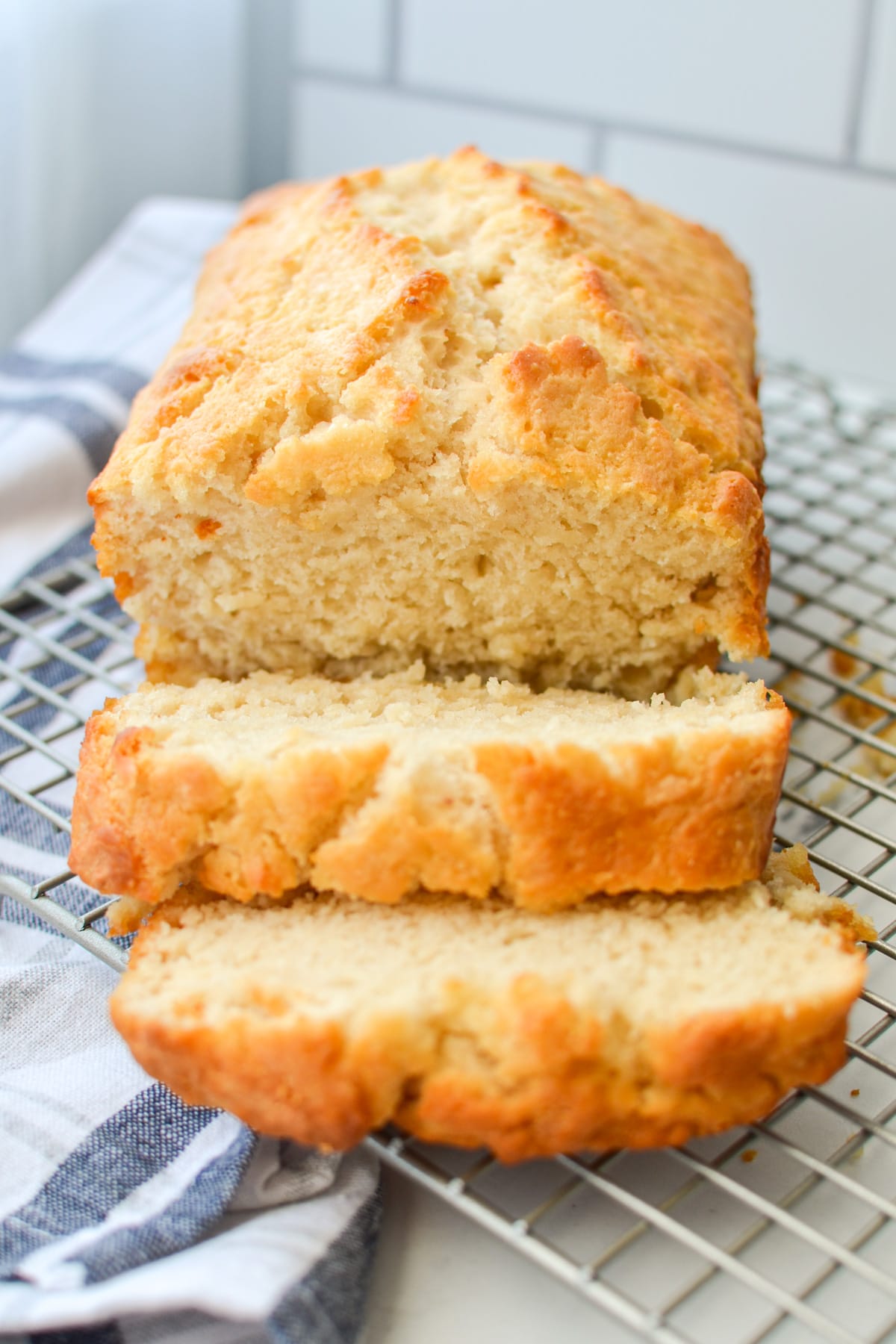 A loaf of sourdough beer bread on a wire rack, sliced and ready to serve.