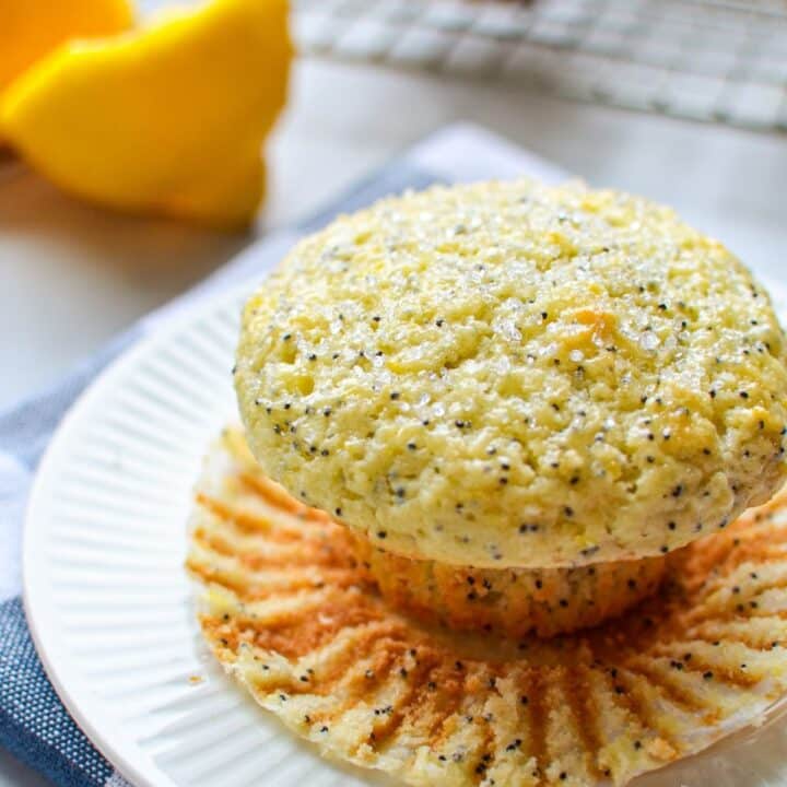 A close up of a lemon poppy seed muffin, with a lemon in the background.