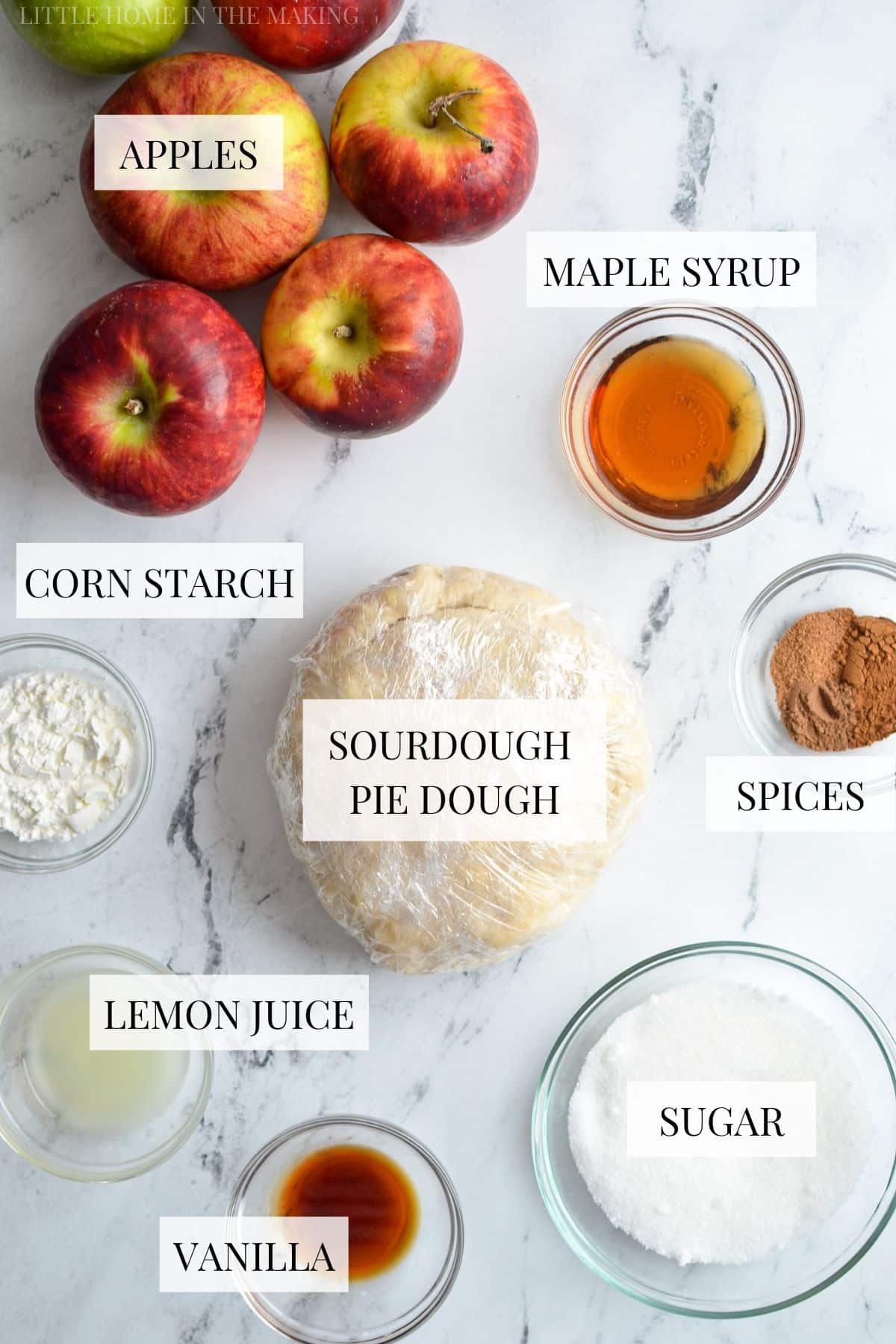 The ingredients needed to make sourdough apple pie, including sourdough pie crust, apples, and maple syrup.