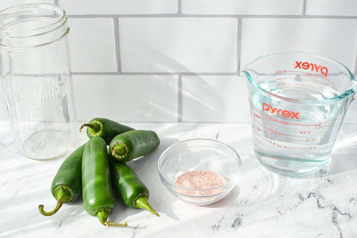 The ingredients needed to make fermented jalapenos, including salt, water and jalapenos.