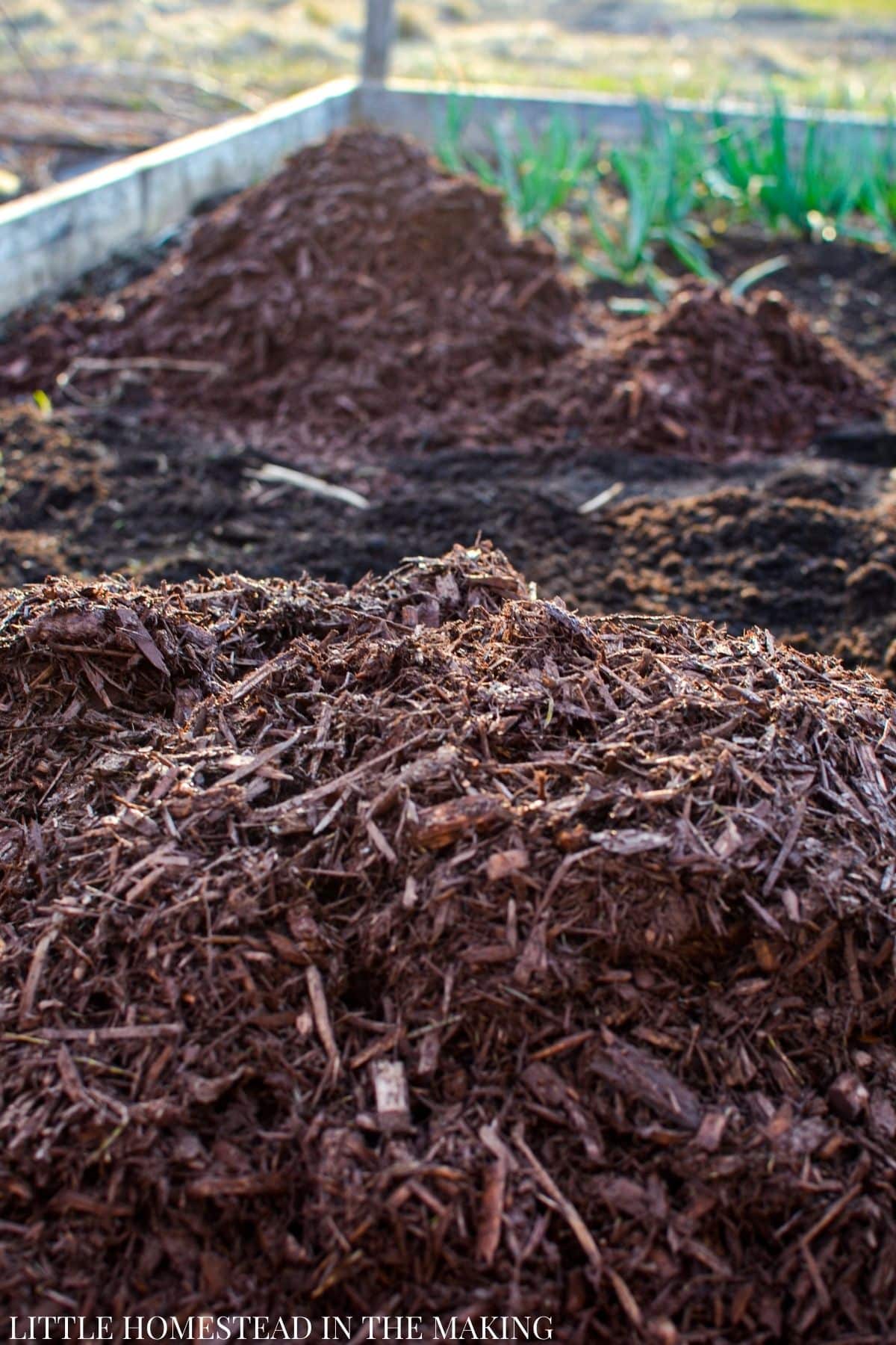 Several piles of mulch inside of a raised bed.