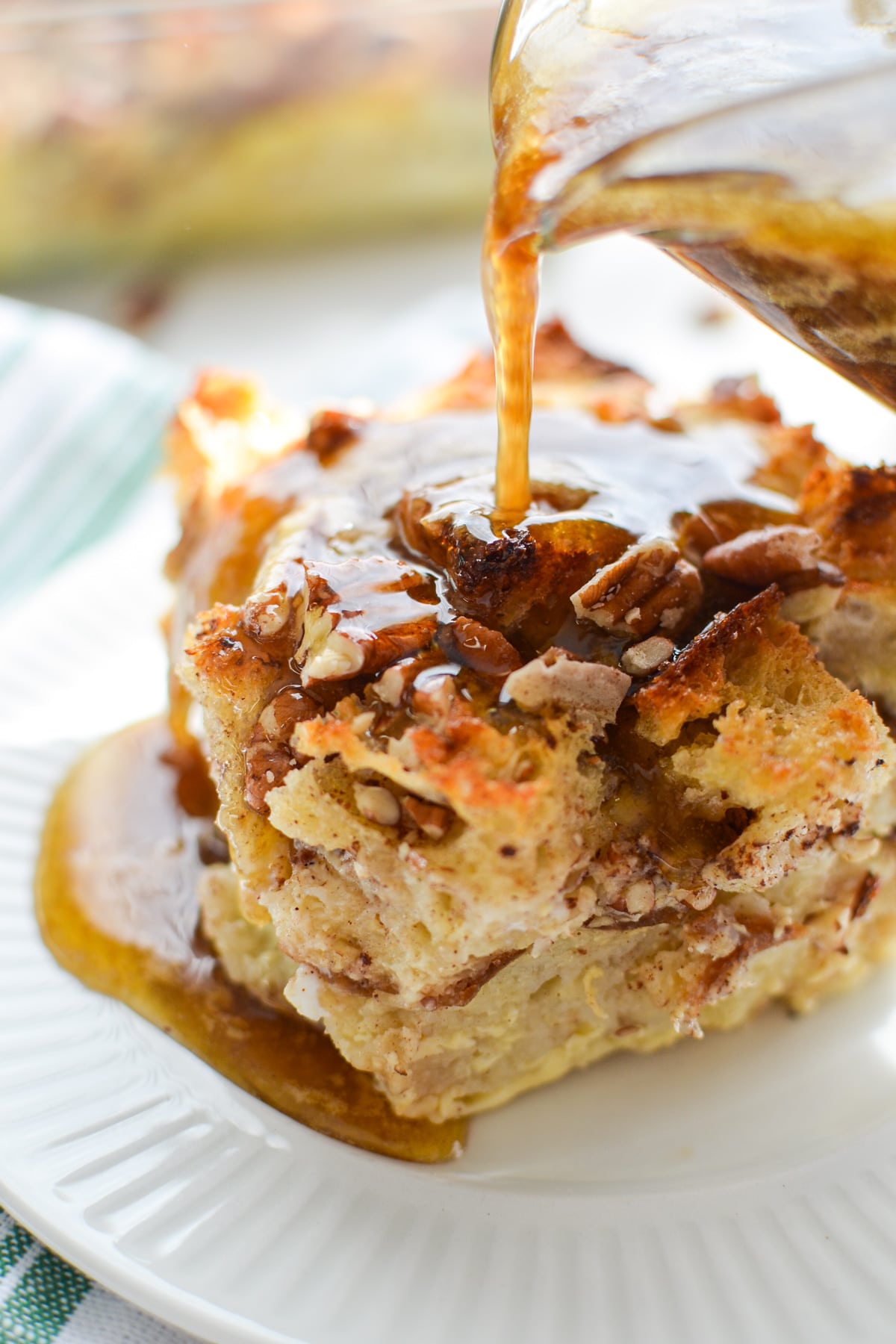 A large square of bread pudding, being drizzled with a brown sugar topping.
