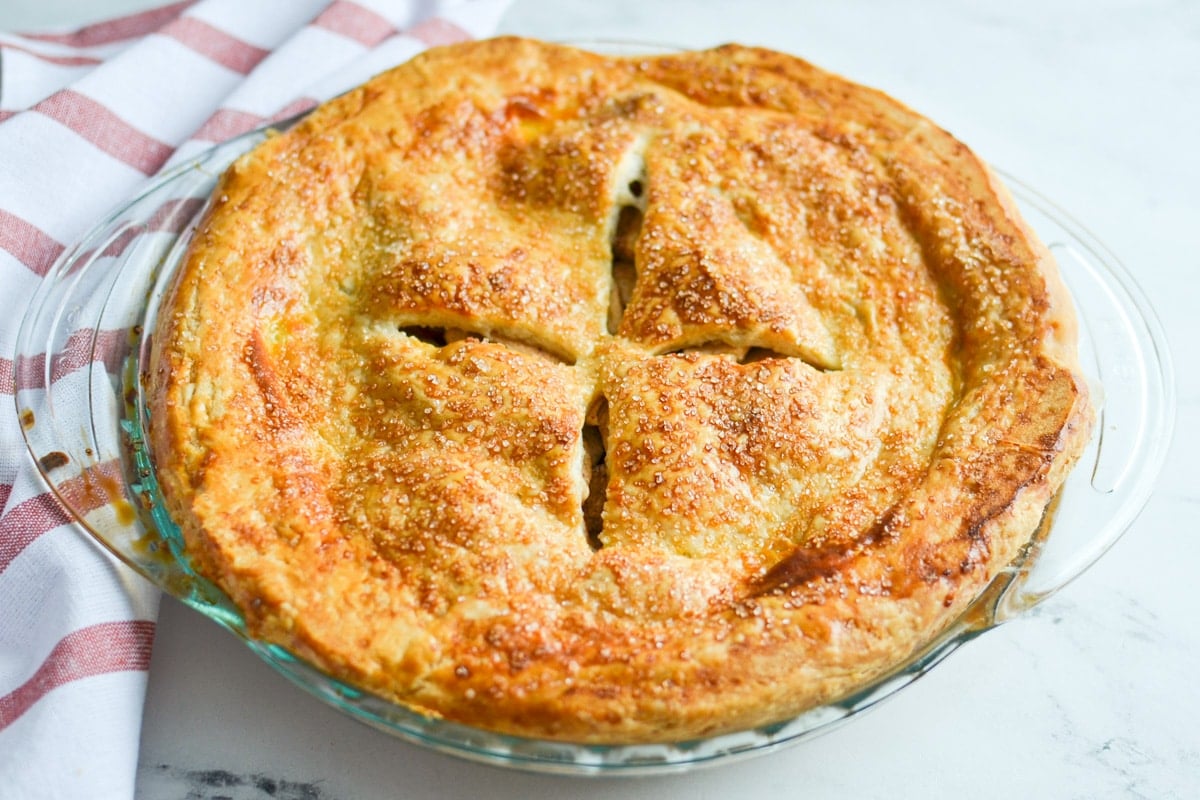 A fully baked double crust pie, resting on a red and white stripe napkin.