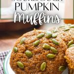 A close up of a plate of muffins, topped with pumpkin seeds.
