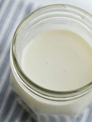 A close up of a jar of milk kefir on a white and blue striped napkin.