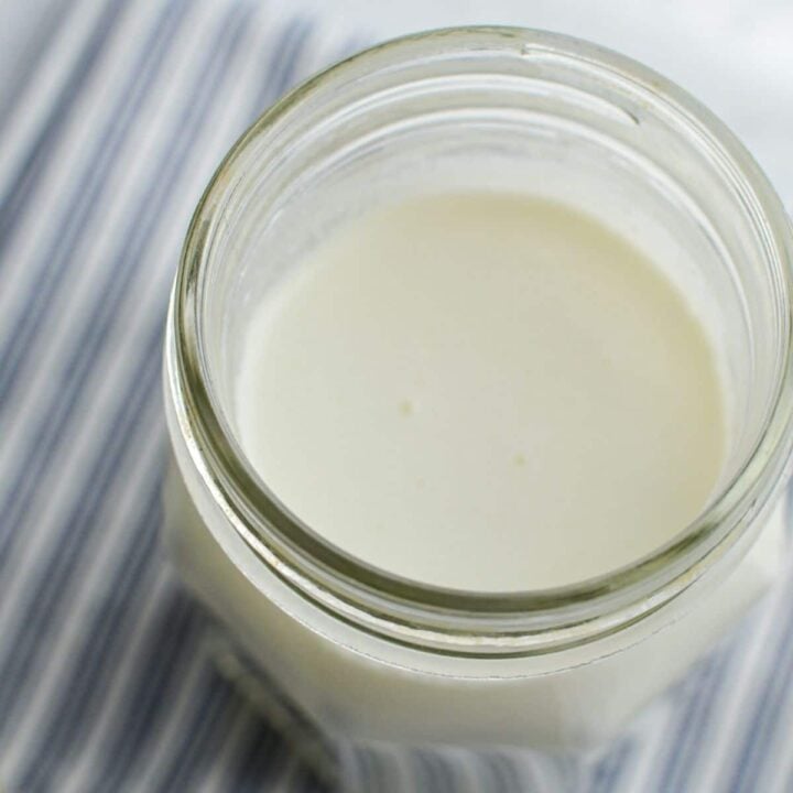 A close up of a jar of milk kefir on a white and blue striped napkin.