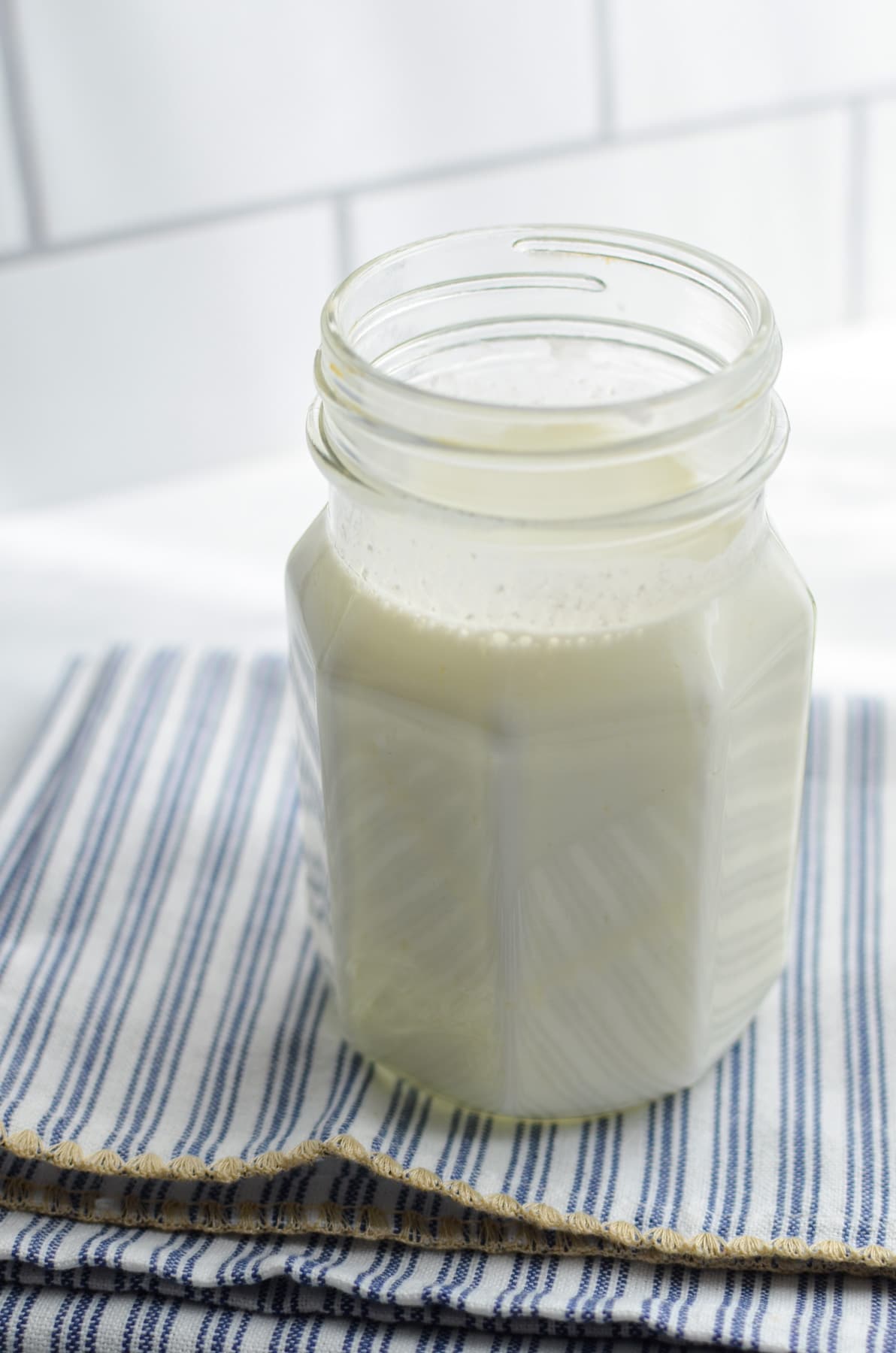 A jar of milk kefir on a striped napkin.