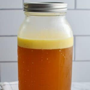 A large jar of beef bone broth with a fat layer on top.
