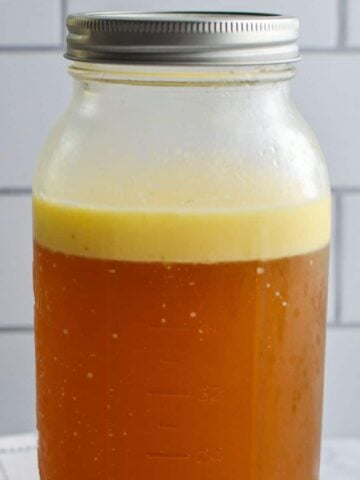 A large jar of beef bone broth with a fat layer on top.