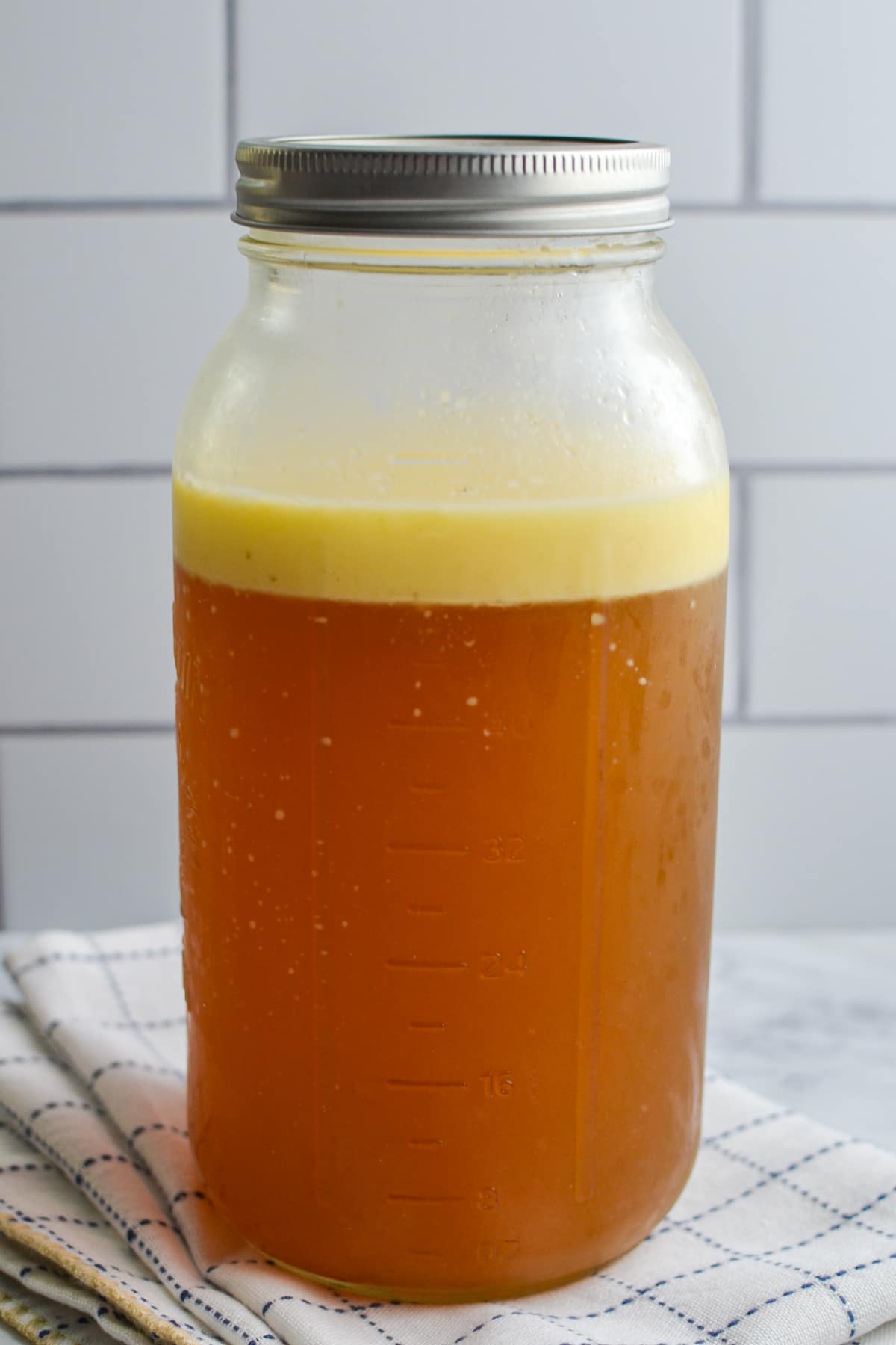 A jar of bone broth that has been chilled with a fat layer on top.