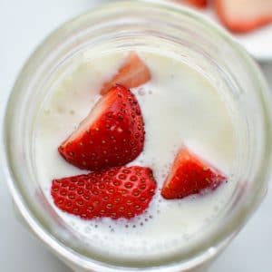 A jar of milk kefir, topped with chopped strawberries.