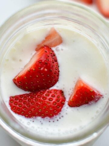 A jar of milk kefir, topped with chopped strawberries.