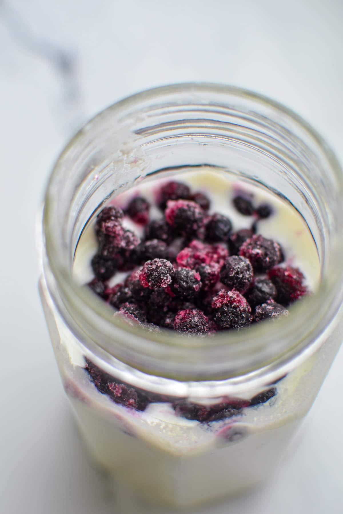 A jar of kefir with frozen blueberries added.