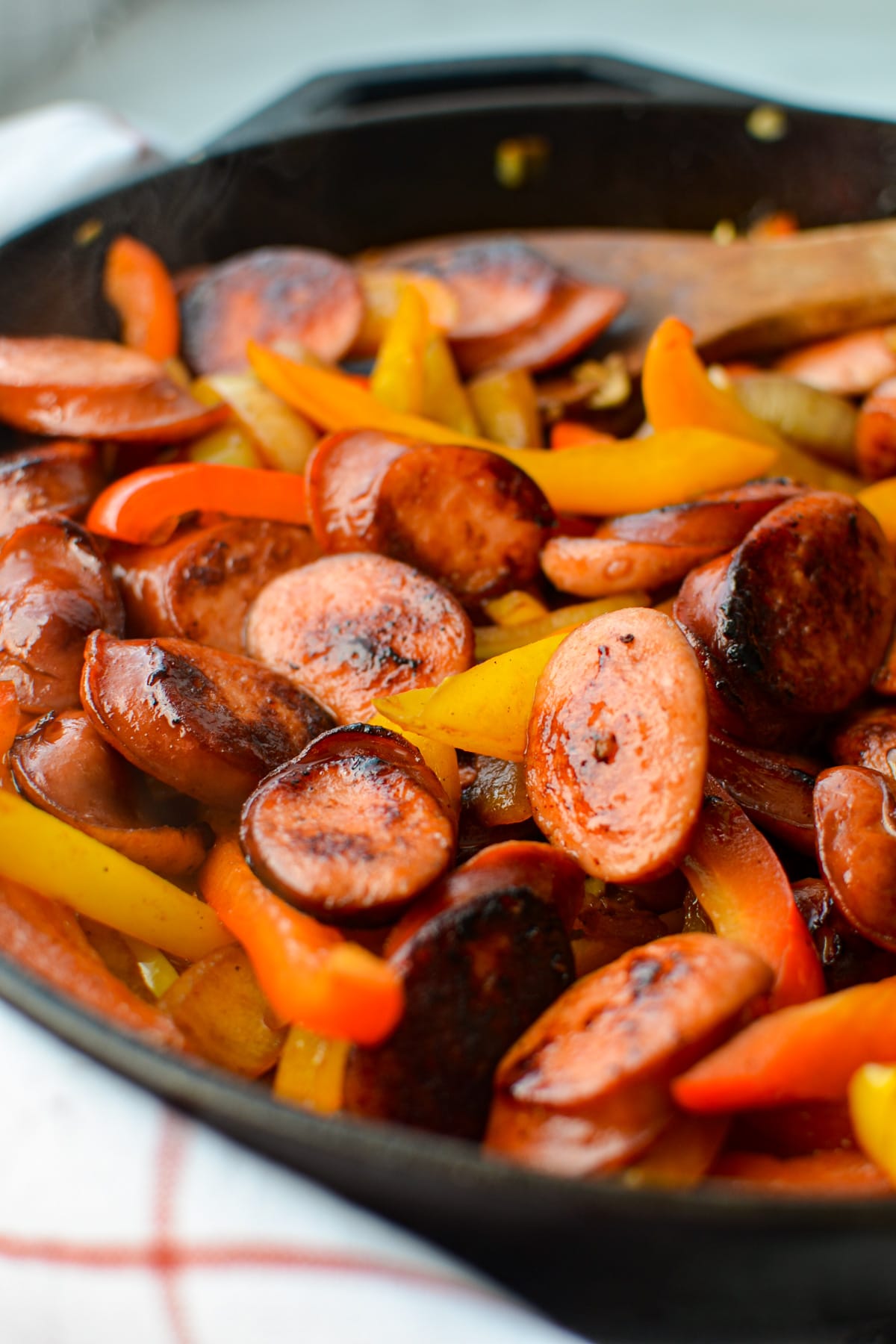 A close up of a skillet with cooked sausage slices and peppers.