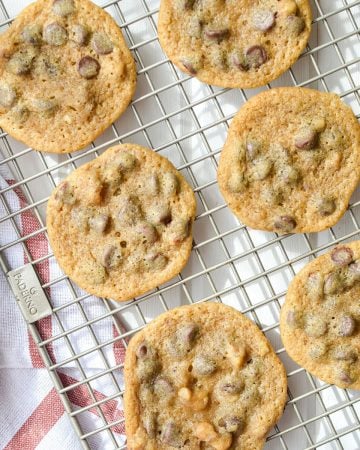 A cooling rack with chocolate chip cookies on it.