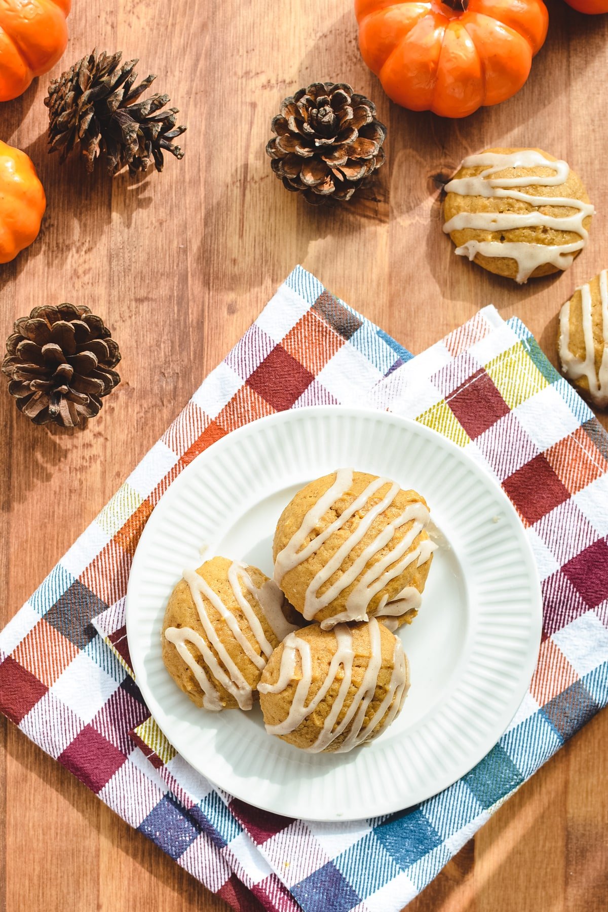 A plate of cookies, surrounded by pinecones and pumpkins.