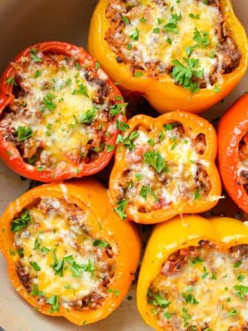 A dutch oven filled with stuffed peppers, and topped with shredded cheese.