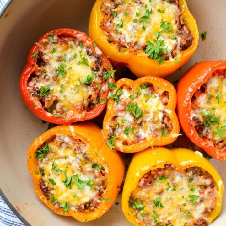 A dutch oven filled with stuffed peppers, and topped with shredded cheese.