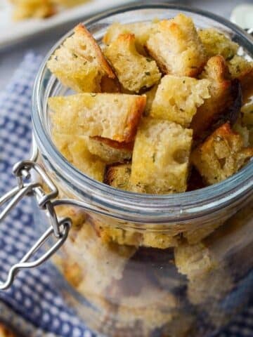 A jar of sourdough croutons resting on a cloth napkin.