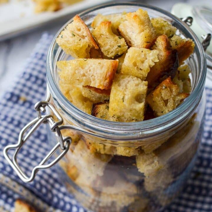 A jar of sourdough croutons resting on a cloth napkin.