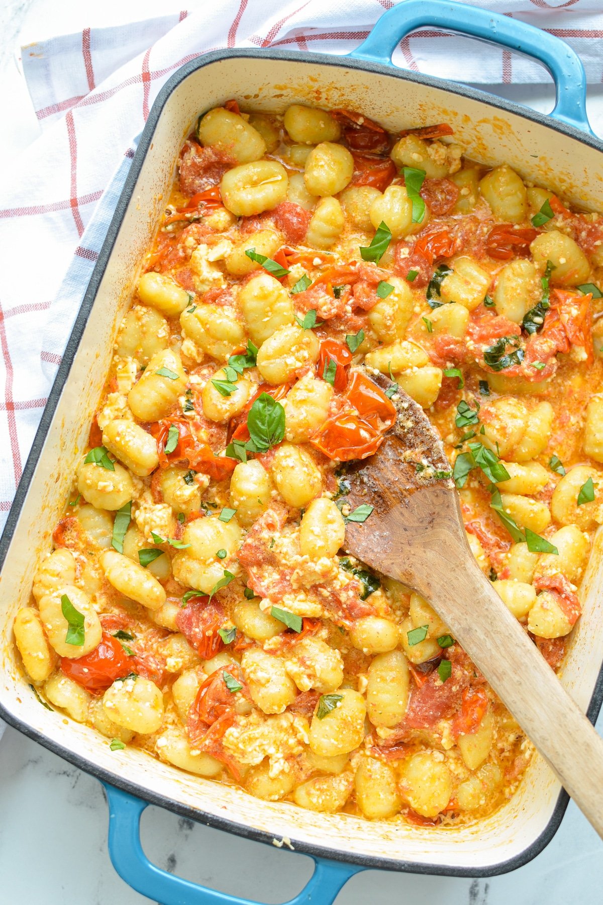 A baking dish with gnocchi pasta tossed with cherry tomatoes and basil.