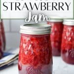 Jars of homemade strawberry jam on a marble surface,