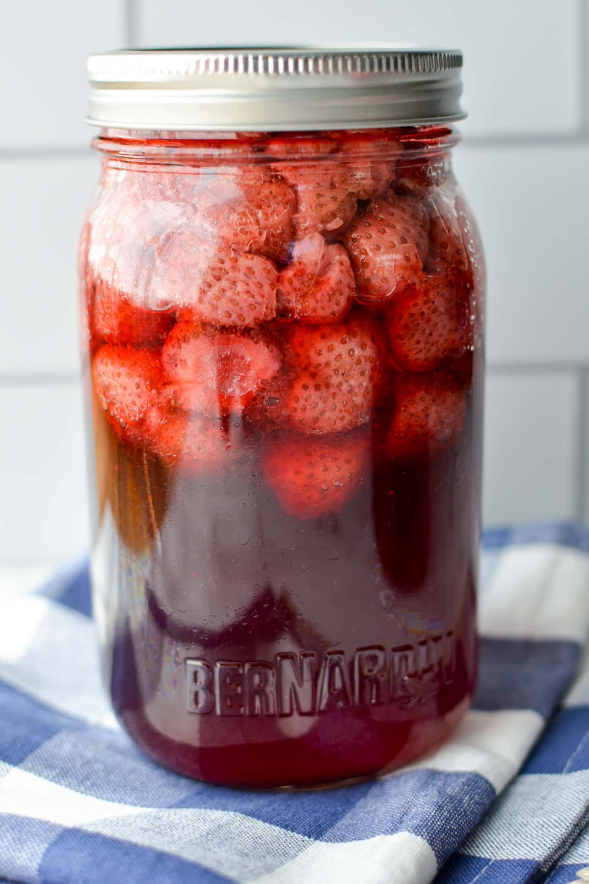 A close up of a jar of strawberries that have been canned in syrup.