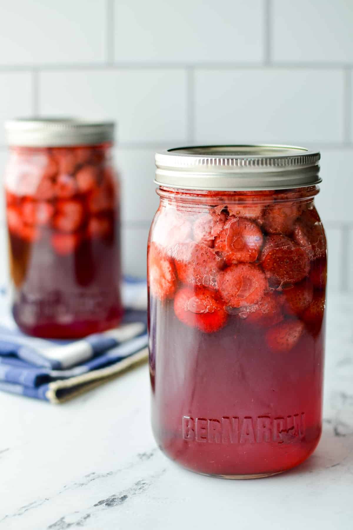Two jars of home canned strawberries in syrup.