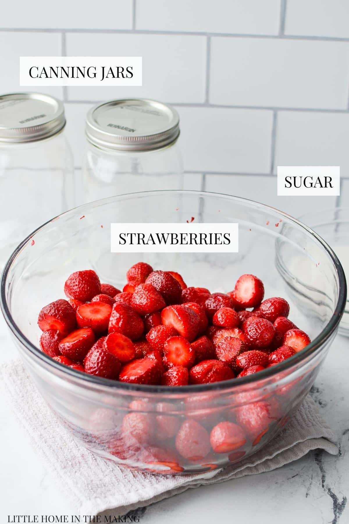 The ingredients needed to can strawberries: canning supplies, strawberries, and sugar.