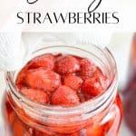 A large jar with hot strawberries and syrup.