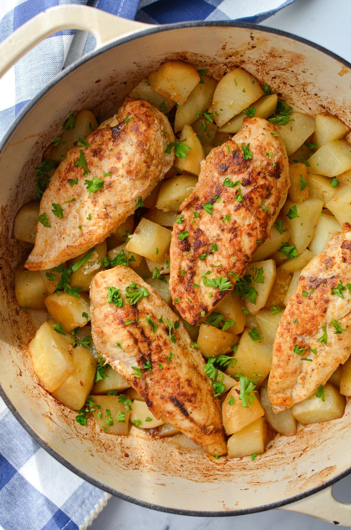 A Dutch Oven with chicken breasts garnished with parsley.