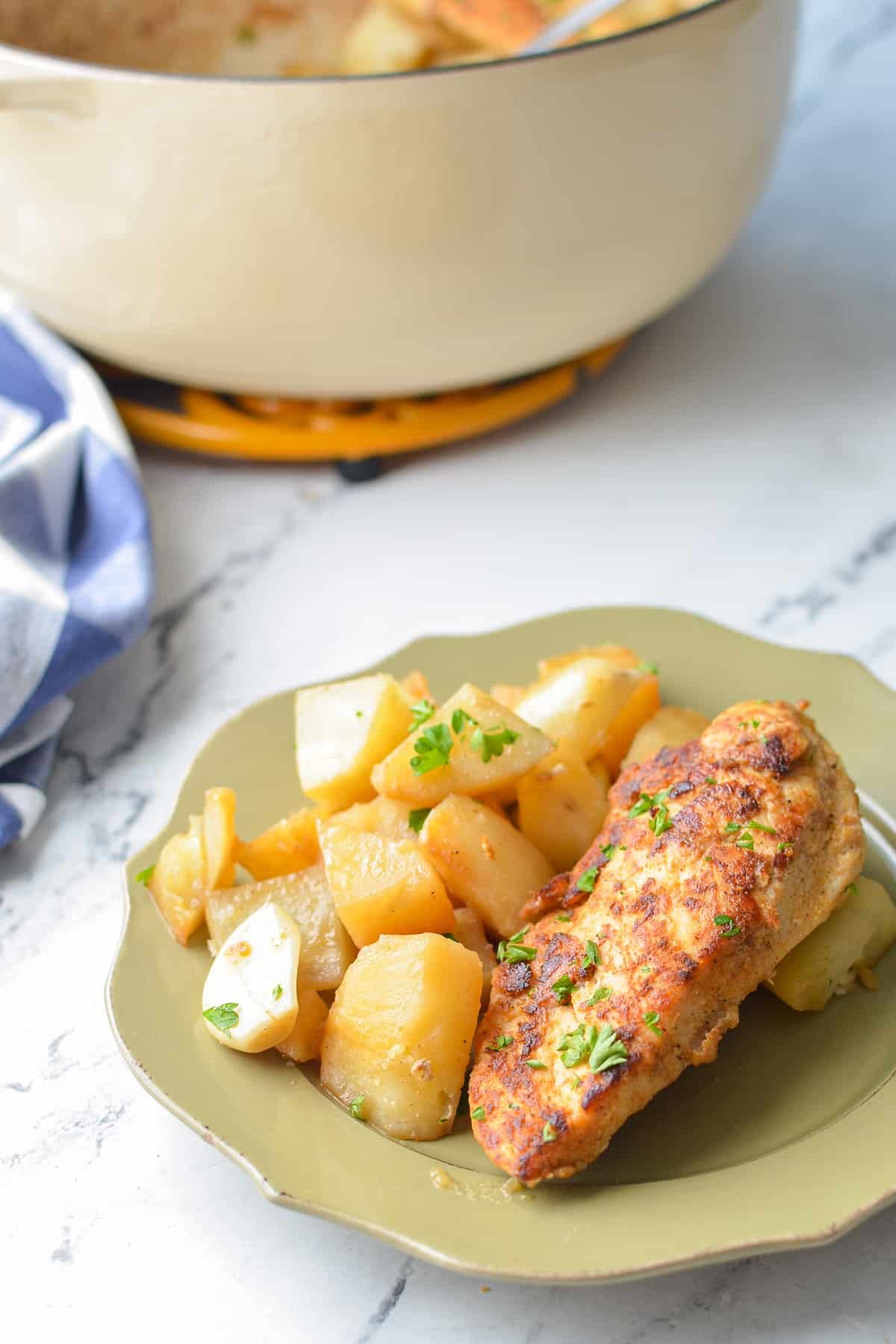 A plate with potatoes and a seasoned chicken breast.