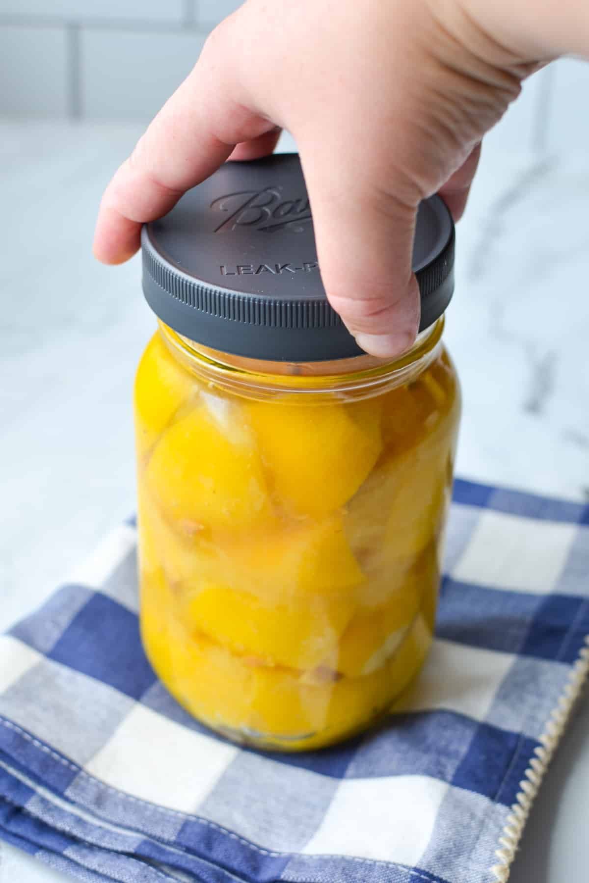 A jar of lemons with a lid being added on.