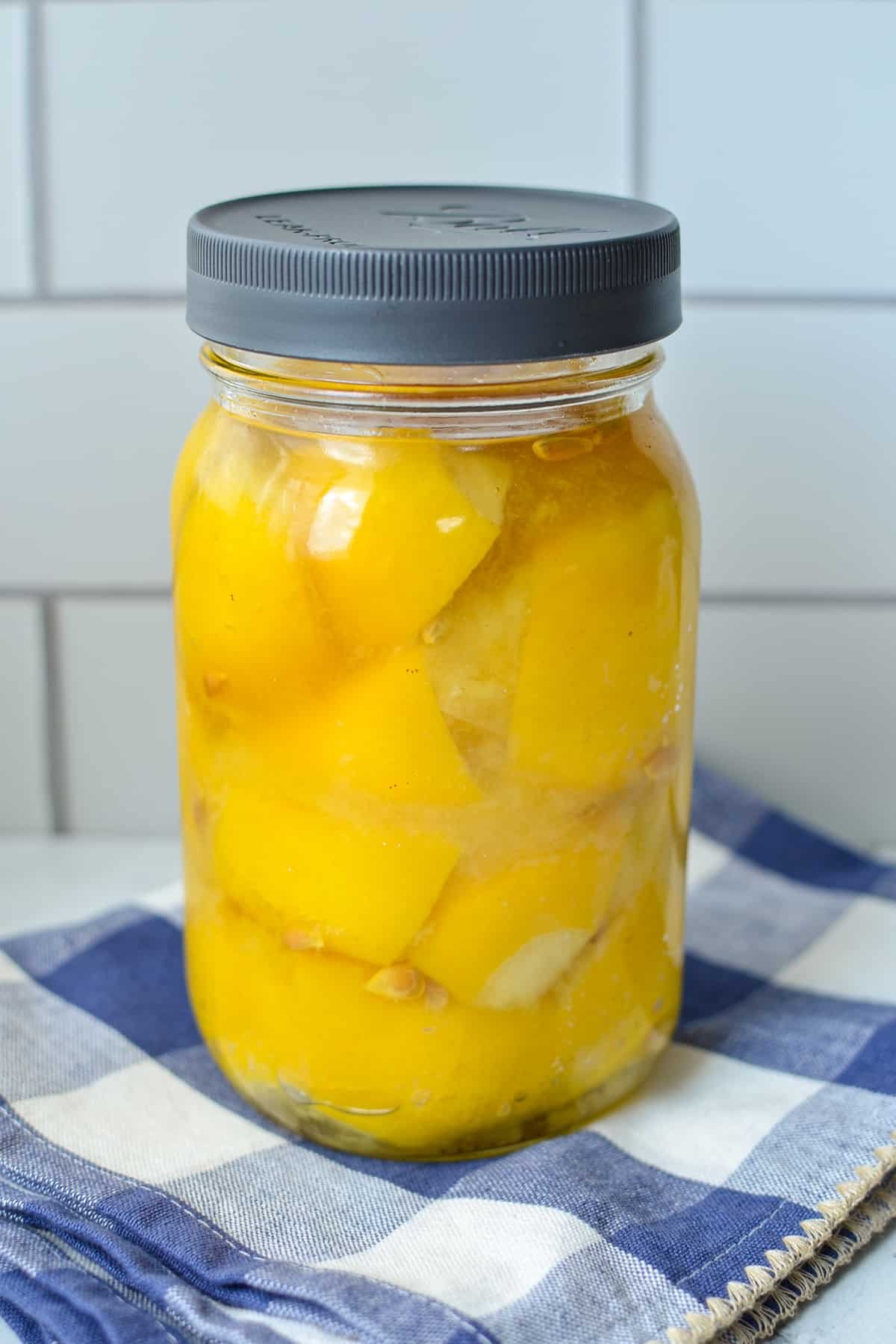 A jar of fermented lemons on a blue check napkin.