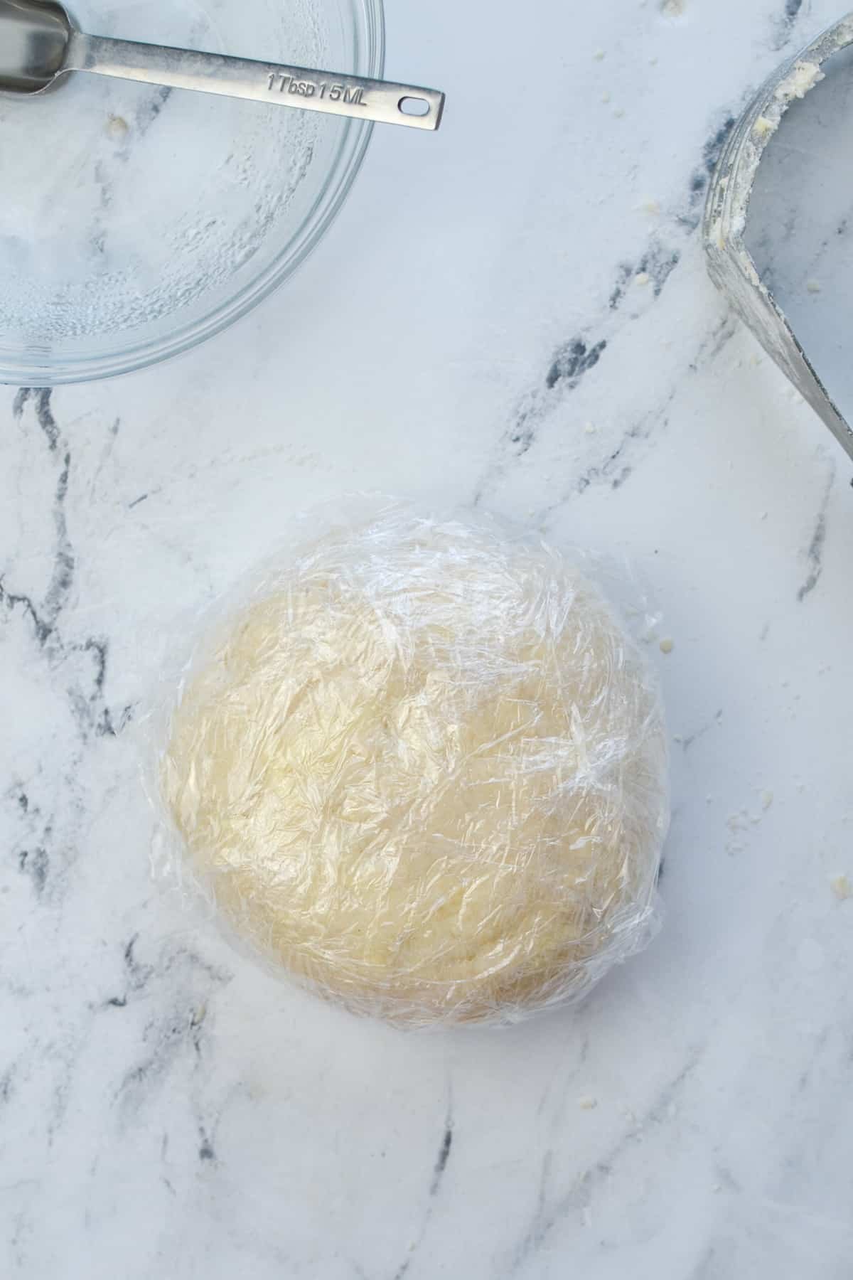 A round of pie dough wrapped in plastic.
