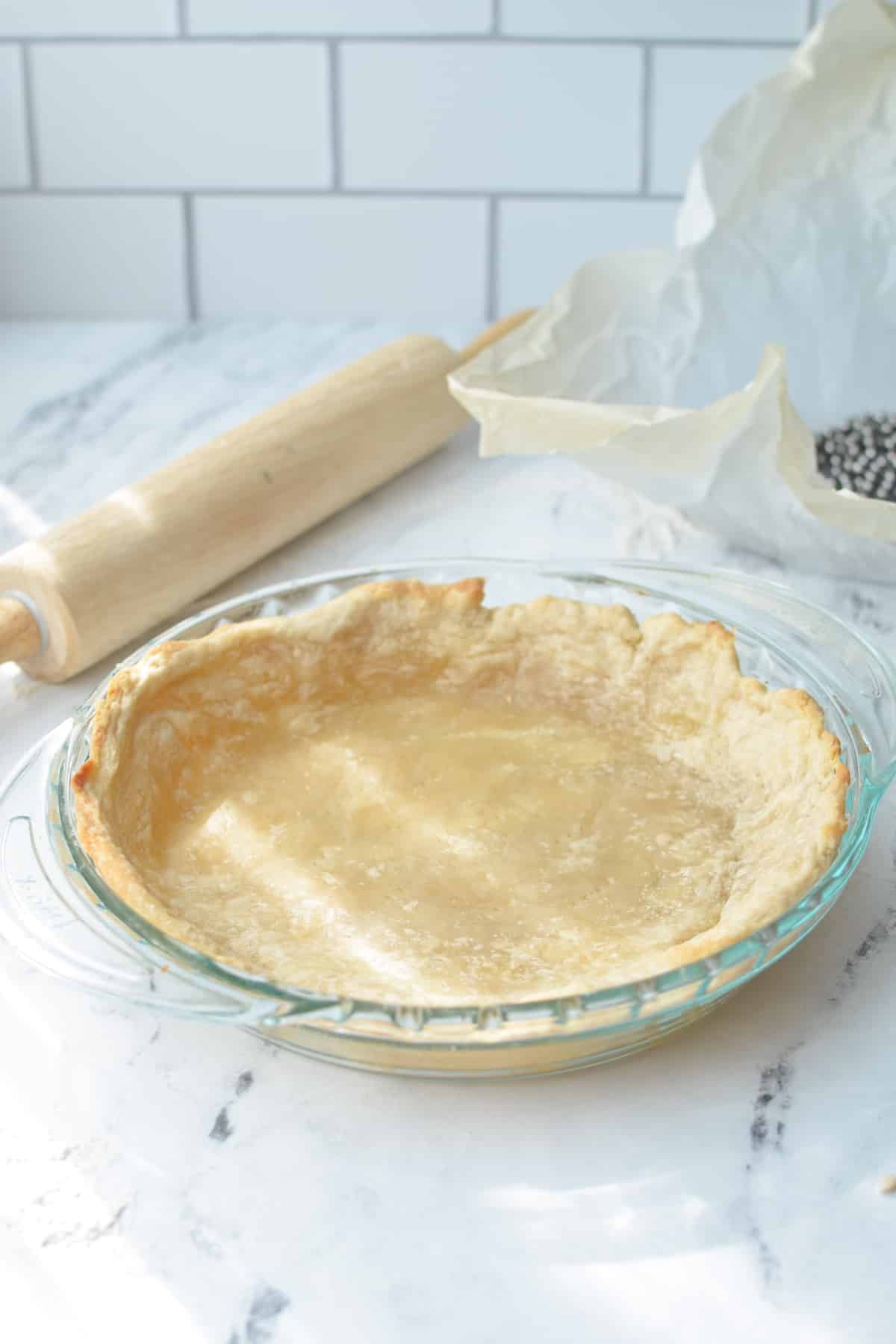 A pie crust partially baked in a pie dish.