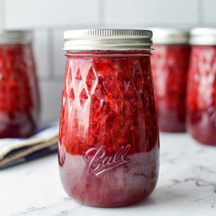 A jar of strawberry jam in a tapered jar.