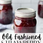 Jars of strawberry jam on a white marble surface.