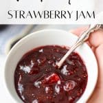 A bowl of strawberry jam with a small spoon in it.