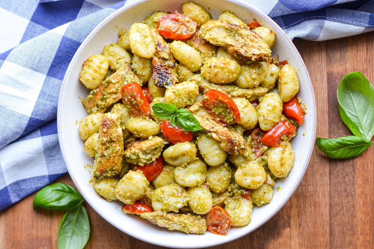 A bowl of gnocchi tossed with pesto and dotted with cherry tomatoes.