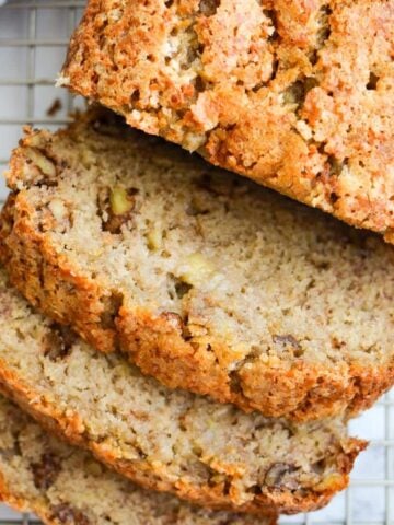 A loaf of sourdough banana bread on a cooling rack, cut into slices.