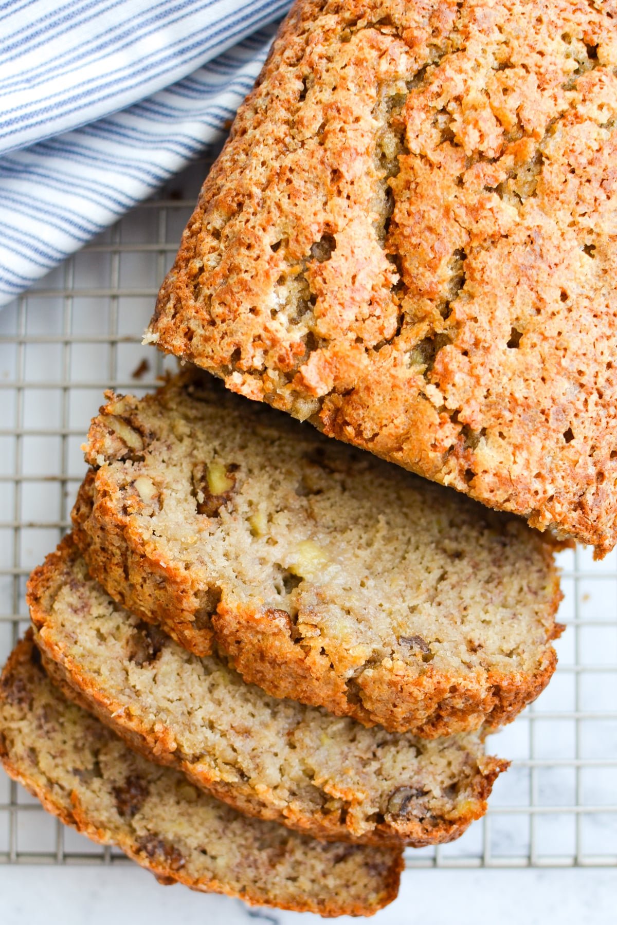 A loaf of banana bread cooling on a rack, cut into slices.