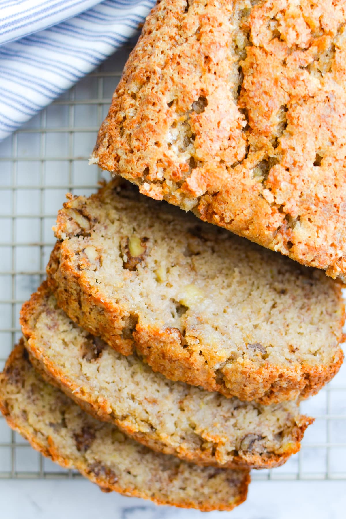 A loaf of sourdough banana bread on a cooling rack, cut into slices.