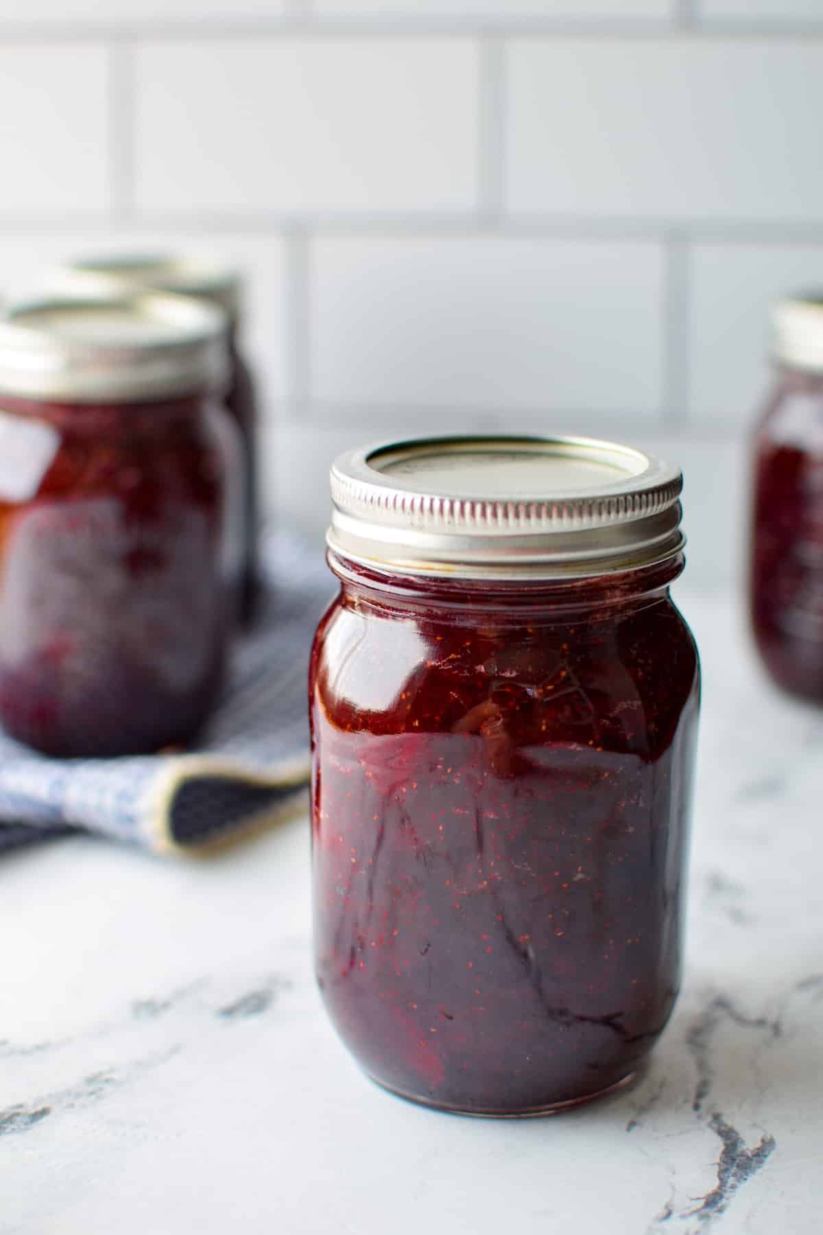 A jar of homemade strawberry jam with other jars in the background.