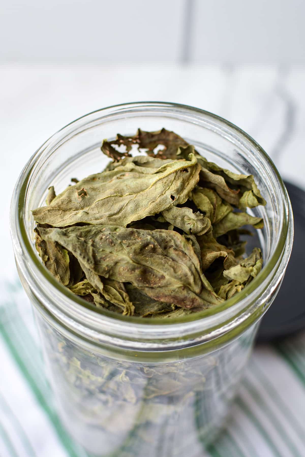 A jar of dried basil leaves.