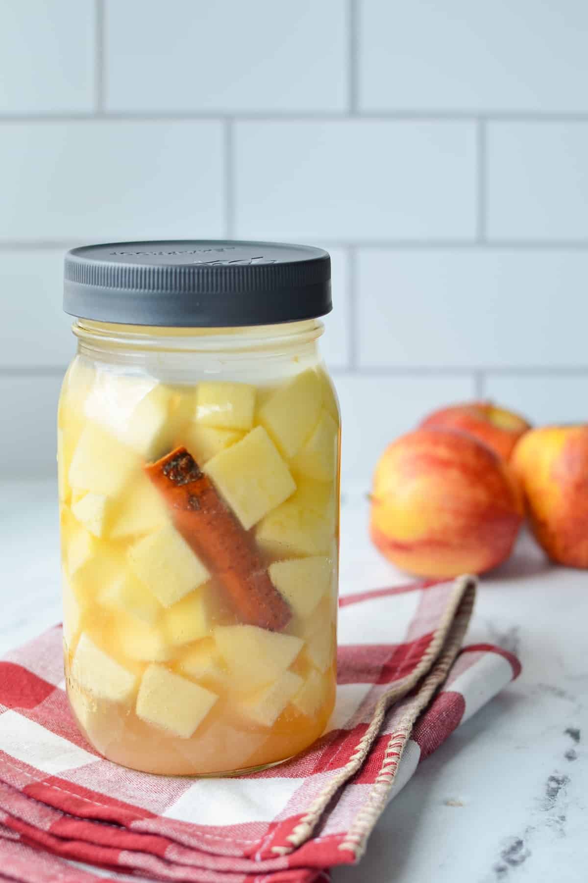 A jar of fermented apples being stored on the counter.