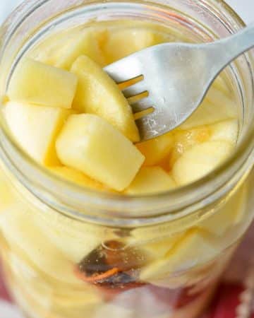 A jar of fermented apples with a fork taking a few out.