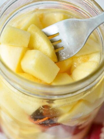 A jar of fermented apples with a fork taking a few out.