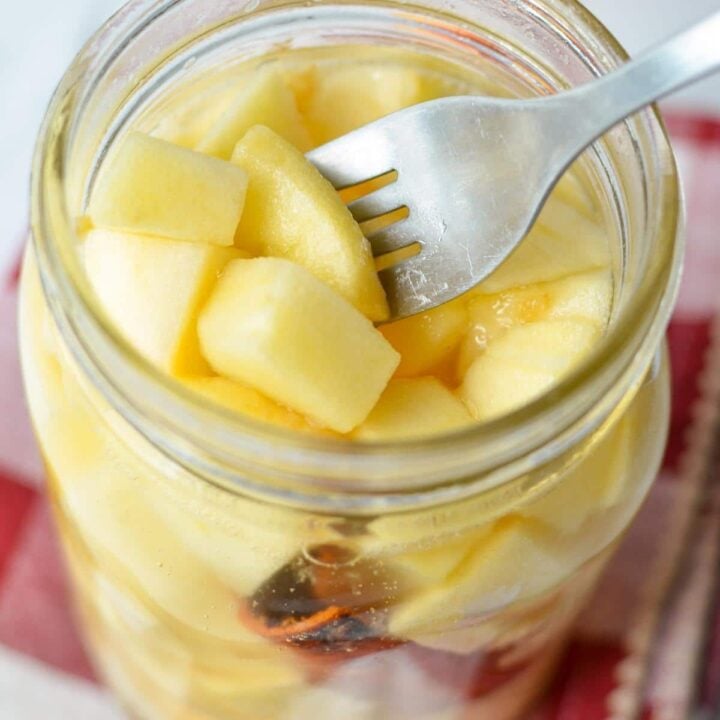 A jar of fermented apples with a fork taking a few out.