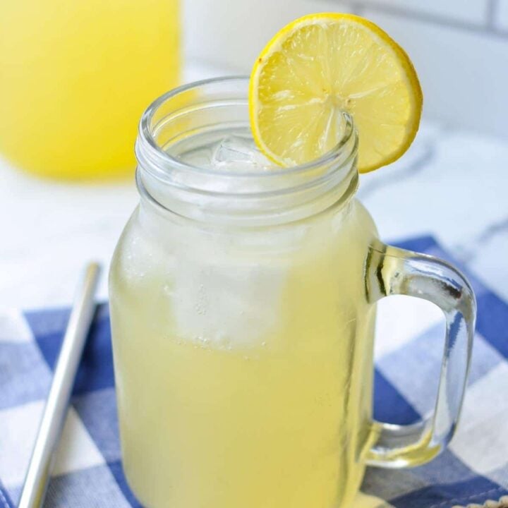 A glass of switchel, served over ice and with lemon slices.